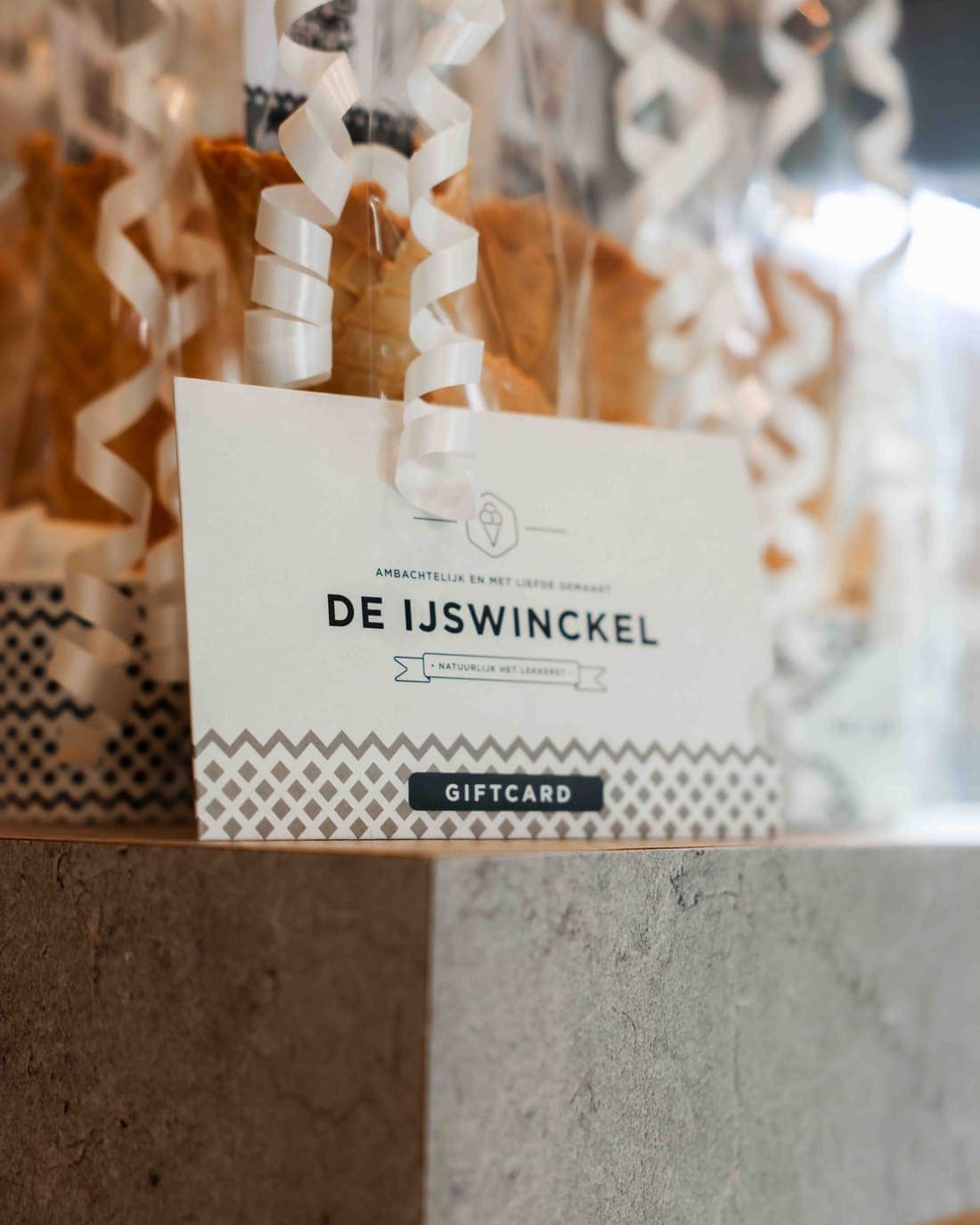 Een cadeaukaart van De IJswinckel voor ingepakte hoorntjes met lint