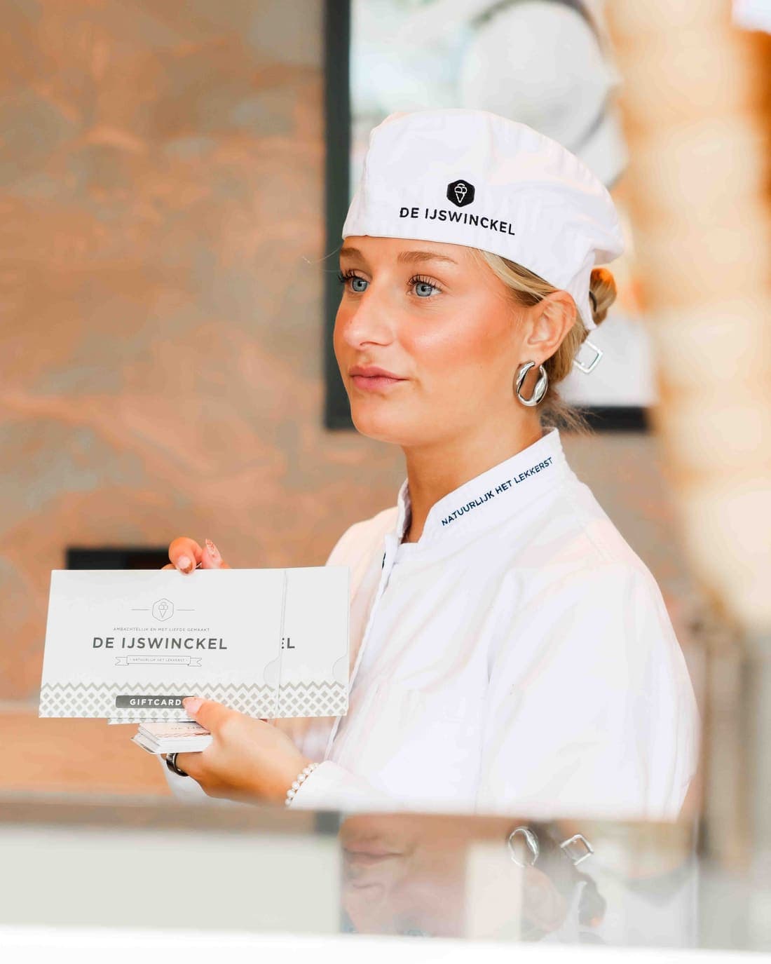 Eine Mitarbeiterin von De IJswinckel mit einem Stapel Geschenkkarten an der Theke