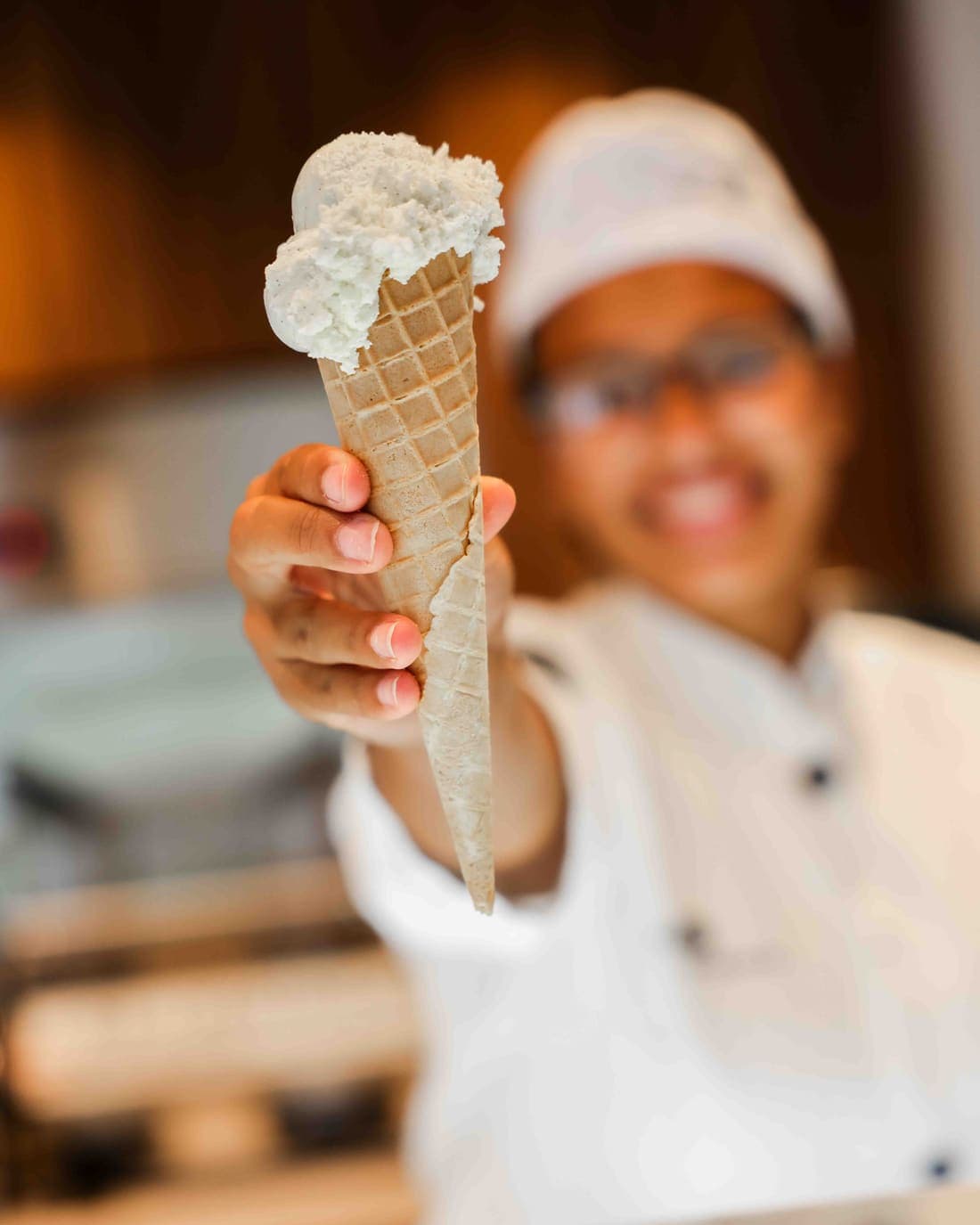Eine Mitarbeiterin von De IJswinckel reicht eine Waffeltüte über die Theke