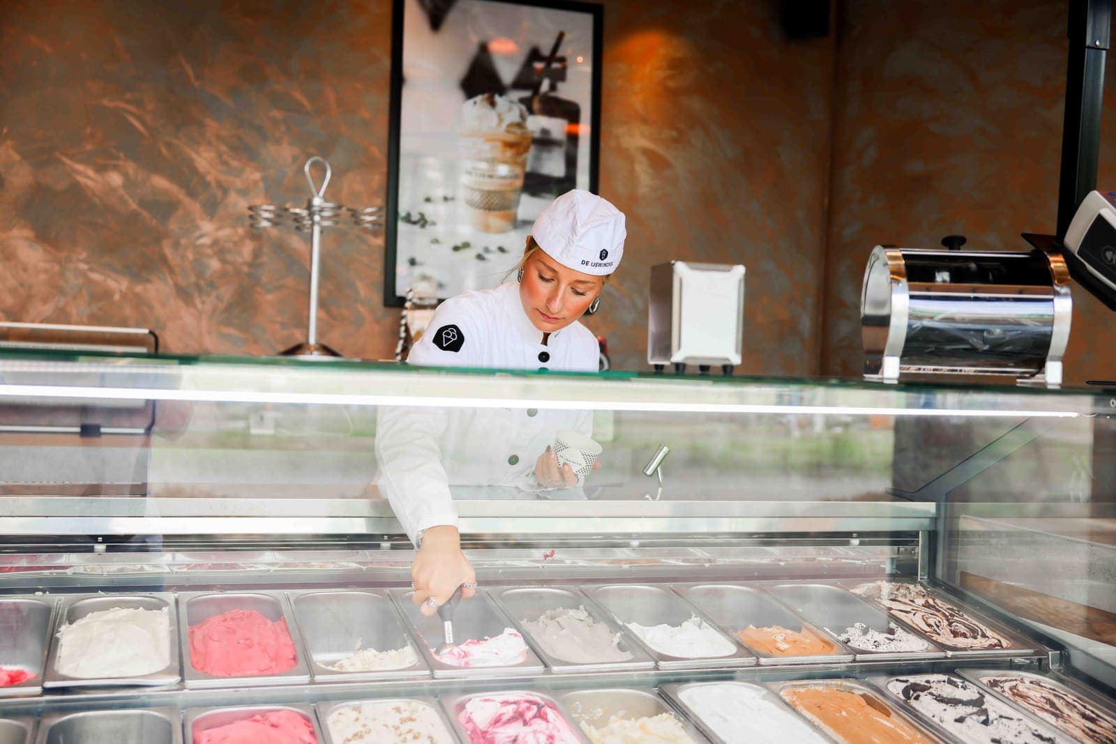 Eine Mitarbeiterin von De IJswinckel schöpft Eis aus der Vitrine